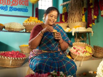 A shopkeeper in her flower shop, holding a Milk Bikis Classic biscuit